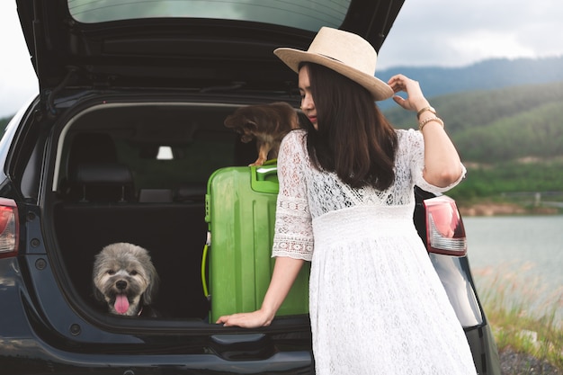 Happy young woman traveler sitting in hatchback car with dogs.