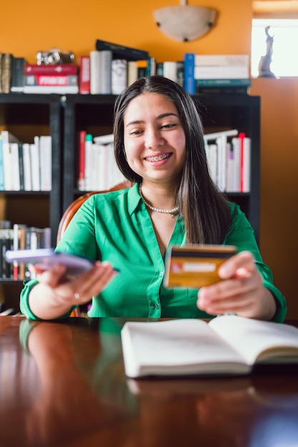 Happy young woman using a credit card to buy online from her personal library. Online shopping