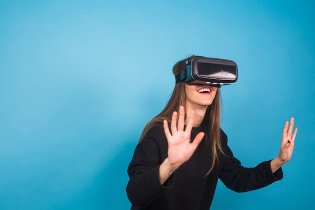 Happy young woman using a virtual reality headset on blue