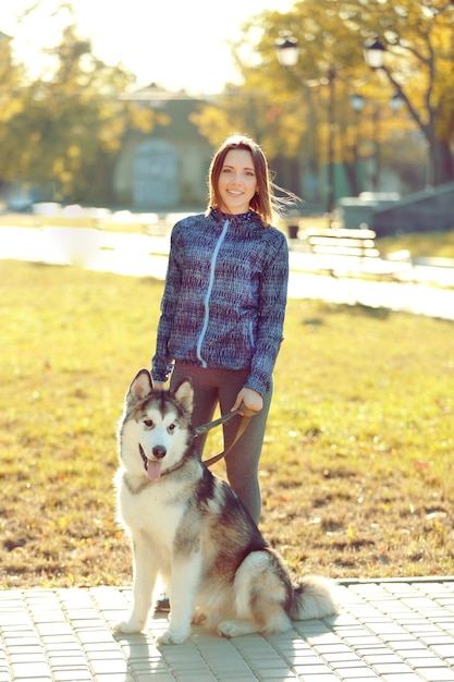 Happy young woman walking with her dog in park