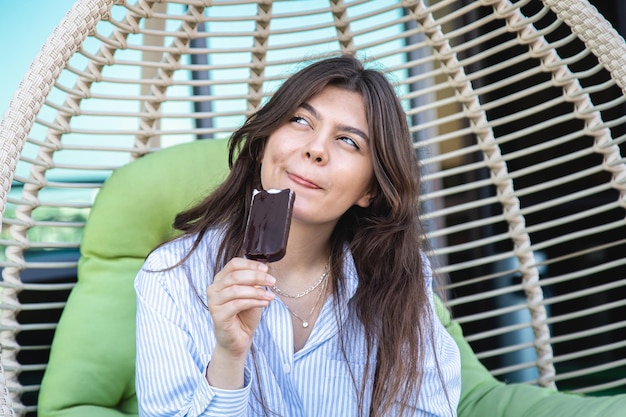 Happy young woman with chocolate ice cream in a hammock