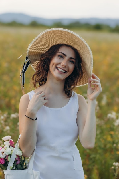 Happy young woman with long hair in dress walking through the summer forest on a sunny day