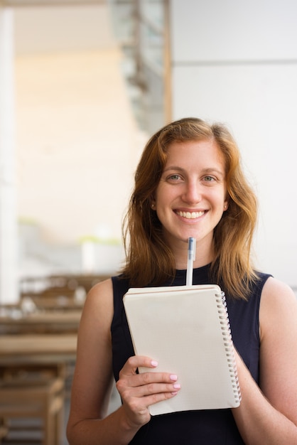 Happy Young Woman with Pen and Notebook at Cafe