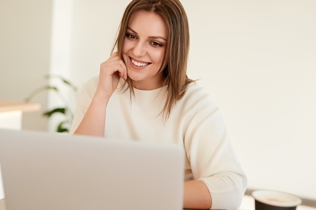 Happy young woman working on laptop in cafe