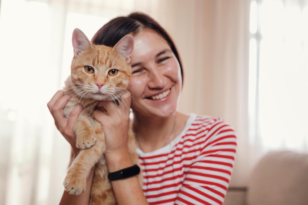 Happy young woman works at home with a laptop and a ginger cat