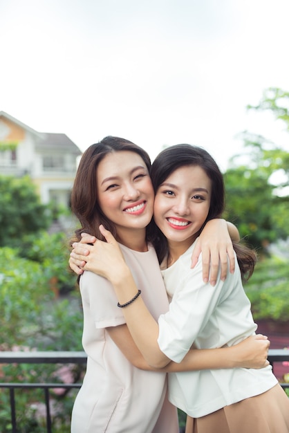 Happy young women friends well-dressed smiling while standing together