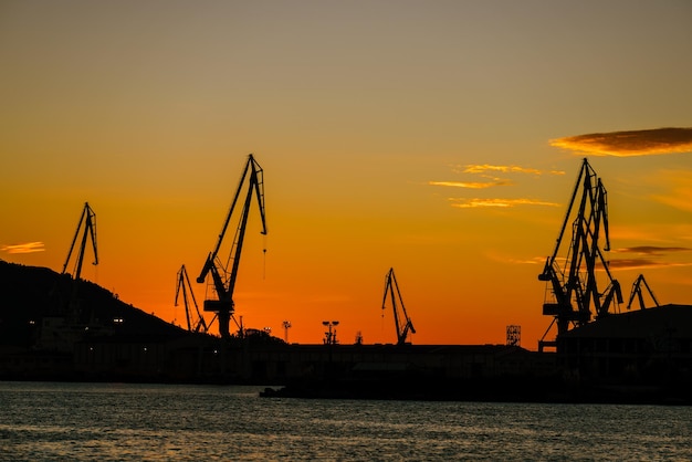 Harbour shipyard cranes against sunset sky in Ferrol Galicia Spain