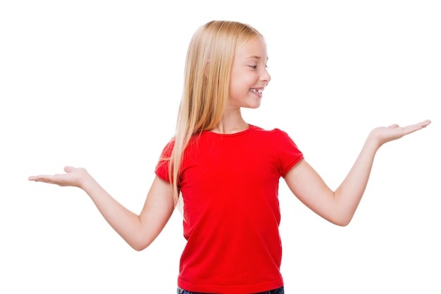 Hard choice. Cute little girl holding copy spaces in hands while standing isolated on white