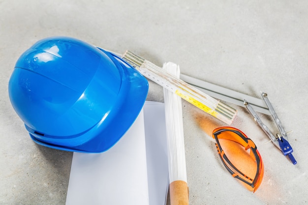 Hard hat, glasses and blueprints at construction site.