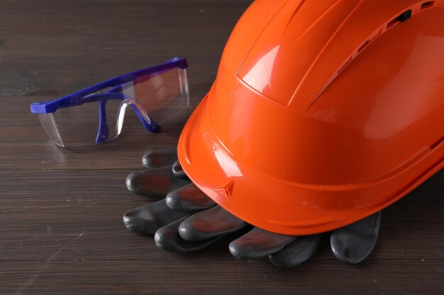 Photo hard hat goggles and gloves on wooden table closeup safety equipment