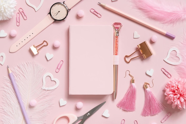 Hardcover notebook, Pink school accessories and hearts on light pink, Top view, textbook mockup. Girly workplace with notebook, scissors, pencil, pen, paperclips, earrings and watch. Back to school