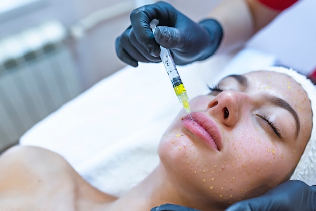 Hardware cosmetology, mesotherapy, portrait of young woman getting treatment of forehead zone 