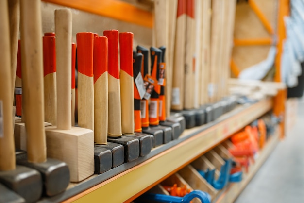 Hardware store assortment, shelf with hammers, nobody. Building materials and tools choice in diy shop, rows of products on racks