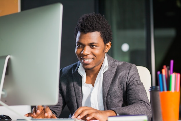 Hardworking smiling guy at office look at computer monitor