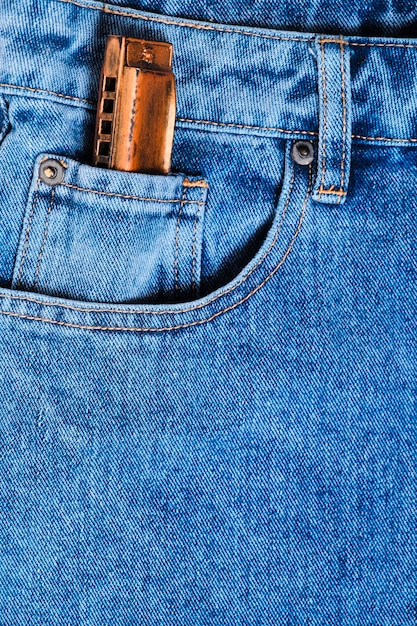 Harmonica musical instrument lies on denim pants