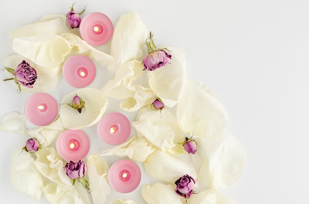 Harmony concept. Burning aroma candles, dried roses and petals on white. Flat lay, copy space