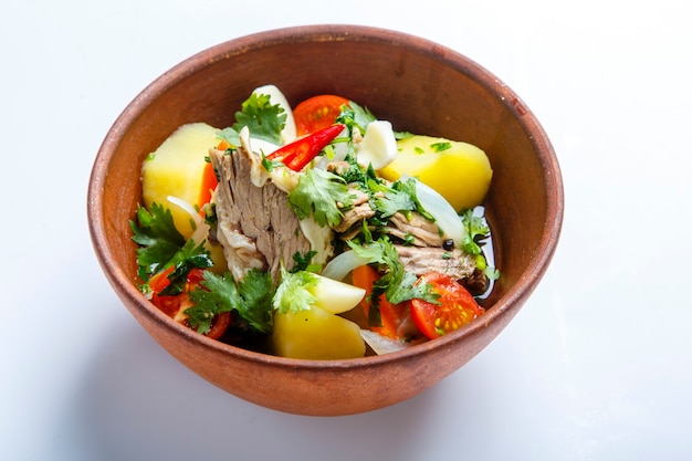 Hashlama in a clay plate. Ingredients Beef ribs, potatoes, herbs, garlic. on a white background