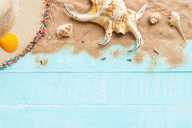 Hat beach and shells on blue wooden background for summer concept.