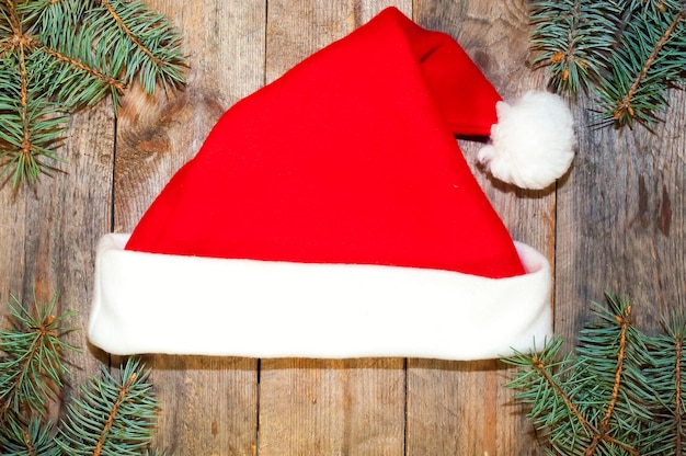 Hat of Santa Claus on the background of fir branches on a wooden table