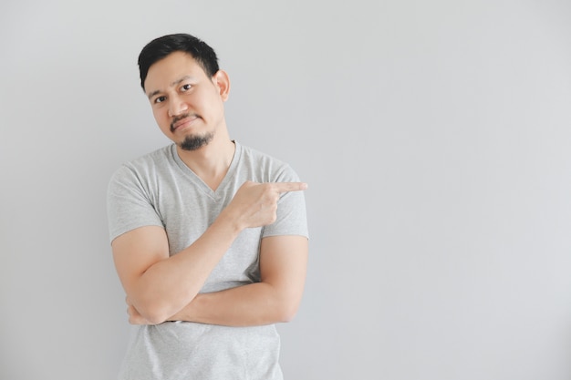 Hate face of man in grey t-shirt with hand point on empty space.