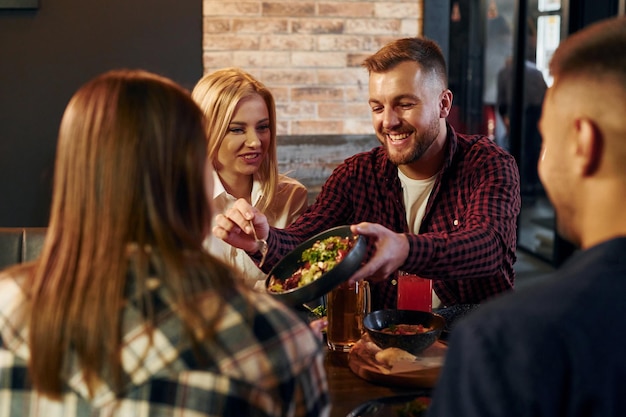 Having conversation Group of young friends sitting together in bar with beer