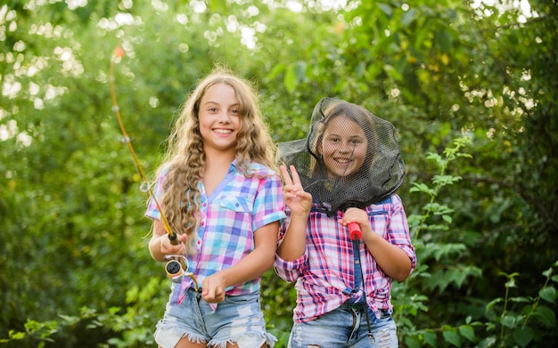 Having fun Fly fishing Kids spend time together fishing Fishing skills Summer hobby Happy smiling children with net and rod Happy childhood Adorable girls nature background Teamwork