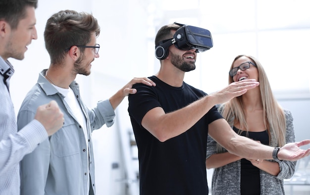 Having fun man wearing virtual reality glasses and pointing with her finger while her colleague touching her shoulders