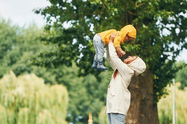 Having fun Mother with her son is having a walk outdoors in the park after the rain