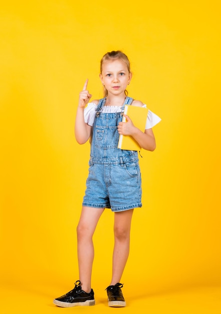 Having new idea Girl read the book Back to school and childhood concept Pupil on yellow background Kid with smart look and casual outfit modern education concept inspired with idea