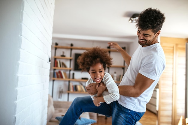 Having so much fun together father plays with his son dad and son having fun in home