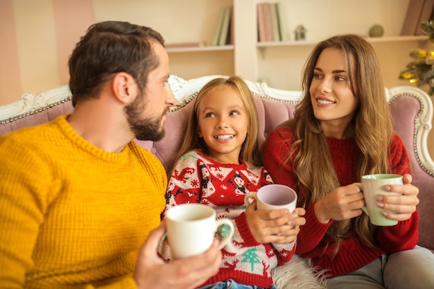 Having tea together. Young family sitting on the sofa and feeling amazing