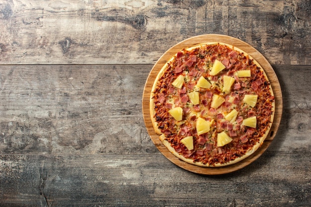 Hawaiian pizza with pineapple,ham and cheese on wooden table