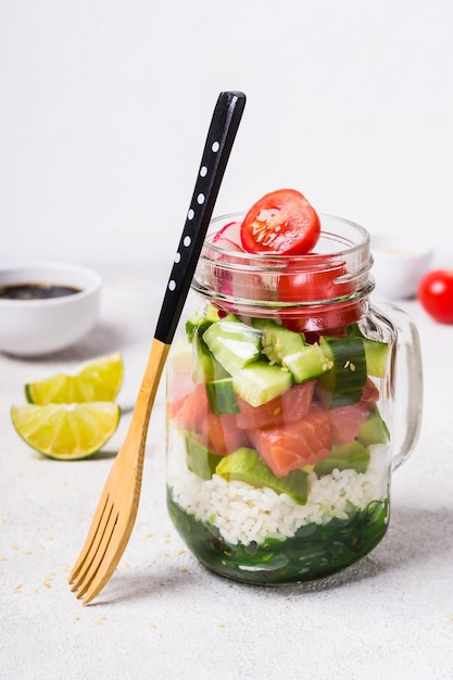 Hawaiian salmon poke salad in glass jar and bamboo fork selective focus