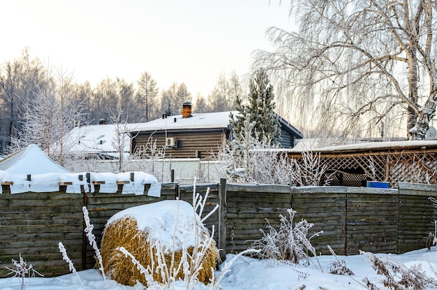 A haystack under the snow near a house in the village.