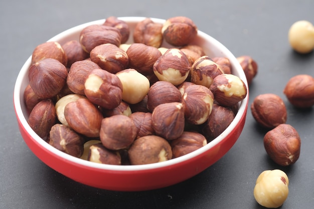 Hazelnuts in a container on black background