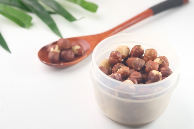 Hazelnuts in a container on white background