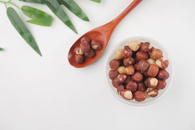 Hazelnuts in a container on white background