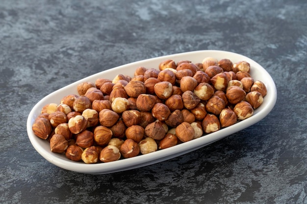 Hazelnuts on plate on dark background