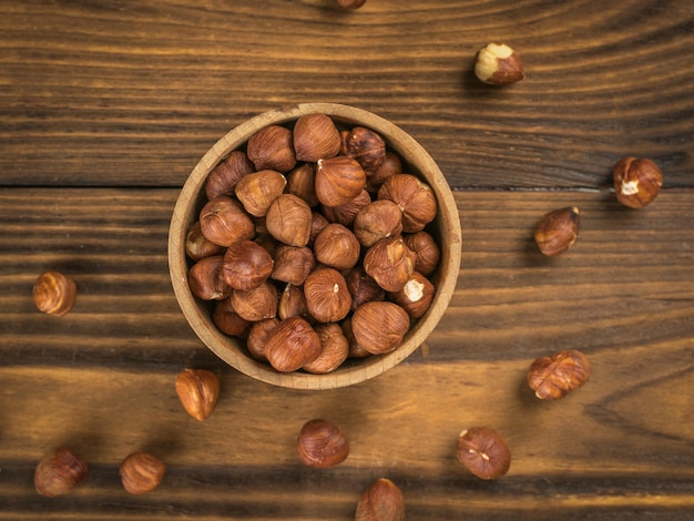 Hazelnuts in a small wooden cup on a wooden background