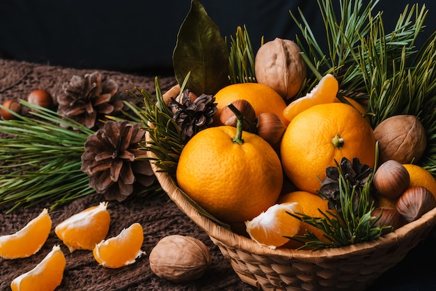 Hazelnuts, walnuts and tangerines decorated with Christmas branches and pine cones