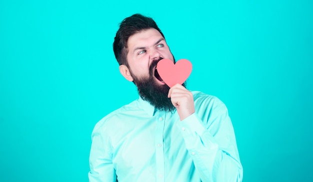 He hates Valentines Boring valentines day Hipster yawning with small heart Sleepy valentine man with heart shaped card Bearded man holding red heart Expressing his love