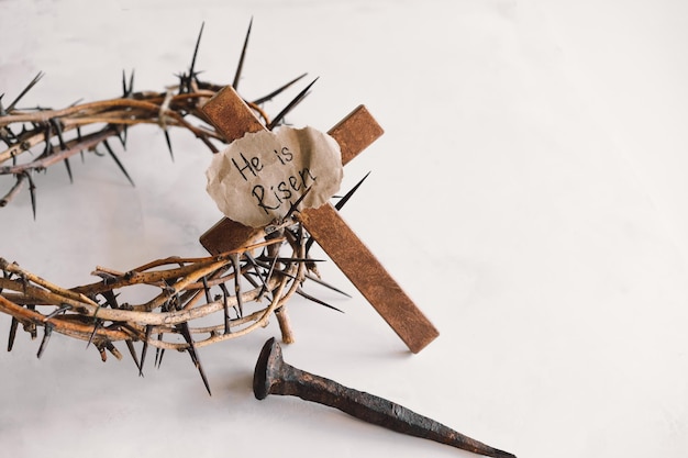 Photo he is risen jesus crown thorns and nails and cross on a white background easter day