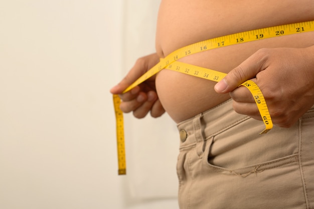 He was measuring his waist with a yellow waist tape because he was too fat.