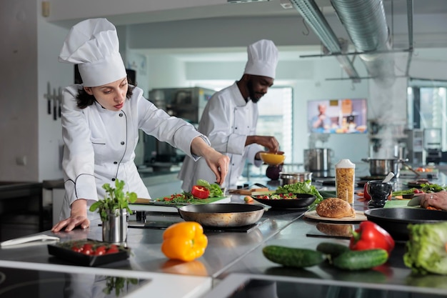 Head chef cooking food for dinner service while adding ingredients to meal. Food industry worker garnishing delicious gourmet dish to be served in restaurant while in professional kitchen.