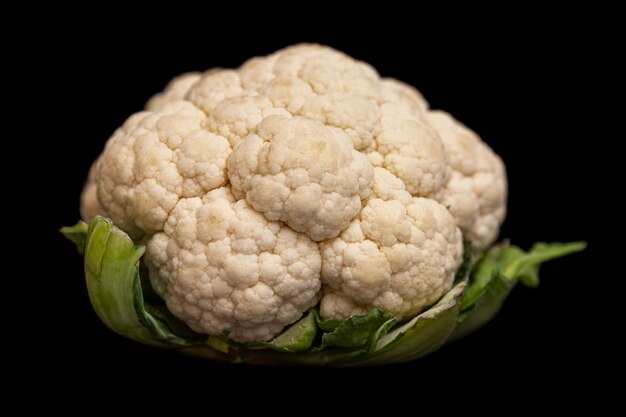 A head of fresh cauliflower. Healthy eating and vegetarianism. Close-up. Black background.