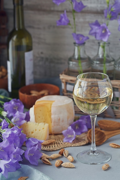 A head of fresh organic cheese served with bread, nuts, white wine and summer flowers. Healthy and organic food concept.