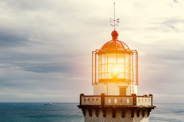 Head of old vintage lighthouse with turned on lamp