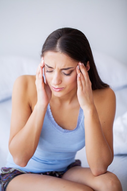 Head pain attractive young woman wake up on her bed looking unhappy and feeling sick