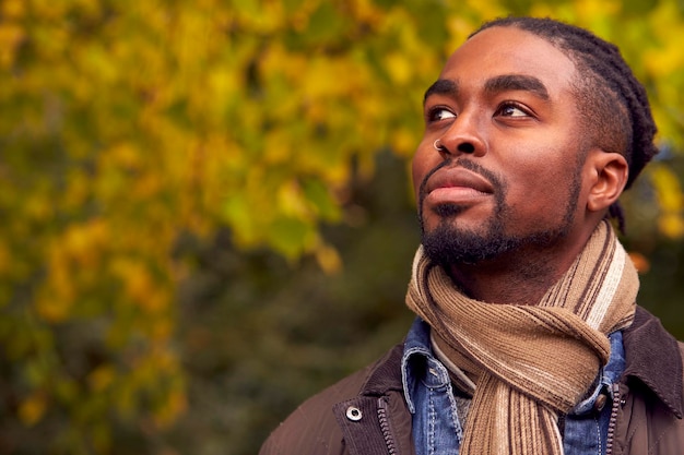 Head And Shoulders Portrait Of Man On Walk Through Autumn Countryside Against Golden Leaves