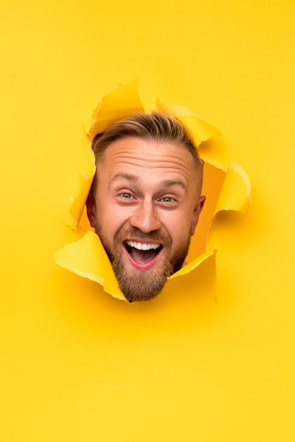 Head of smiling man inside a hole in yellow paper